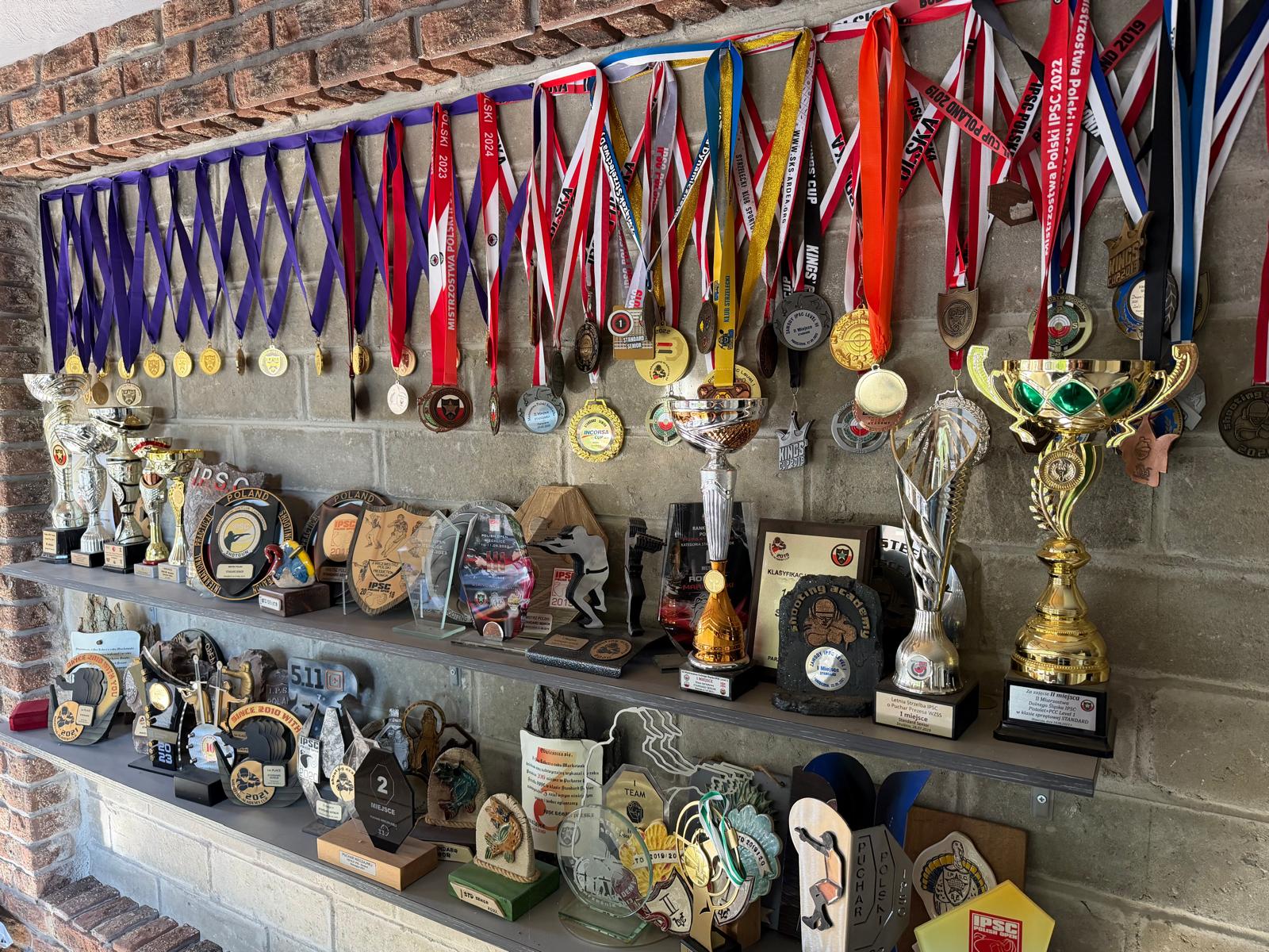 Ściana medali i pucharów Roberta Markowskiego z zawodów strzelectwa dynamicznego IPSC w sklepie strzeleckim Proce i Pestki w Zgierzu.
